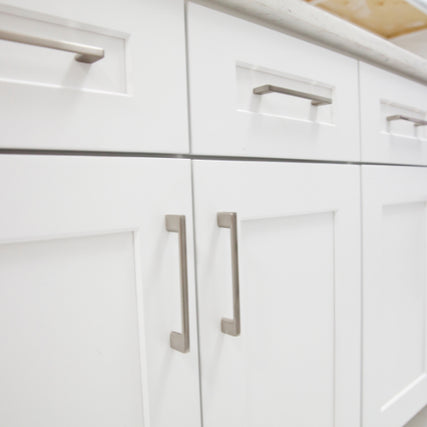 CabinetsClose-up of white kitchen cabinets with sleek silver handles. The bright, clean lines convey a modern and minimalist design aesthetic.
